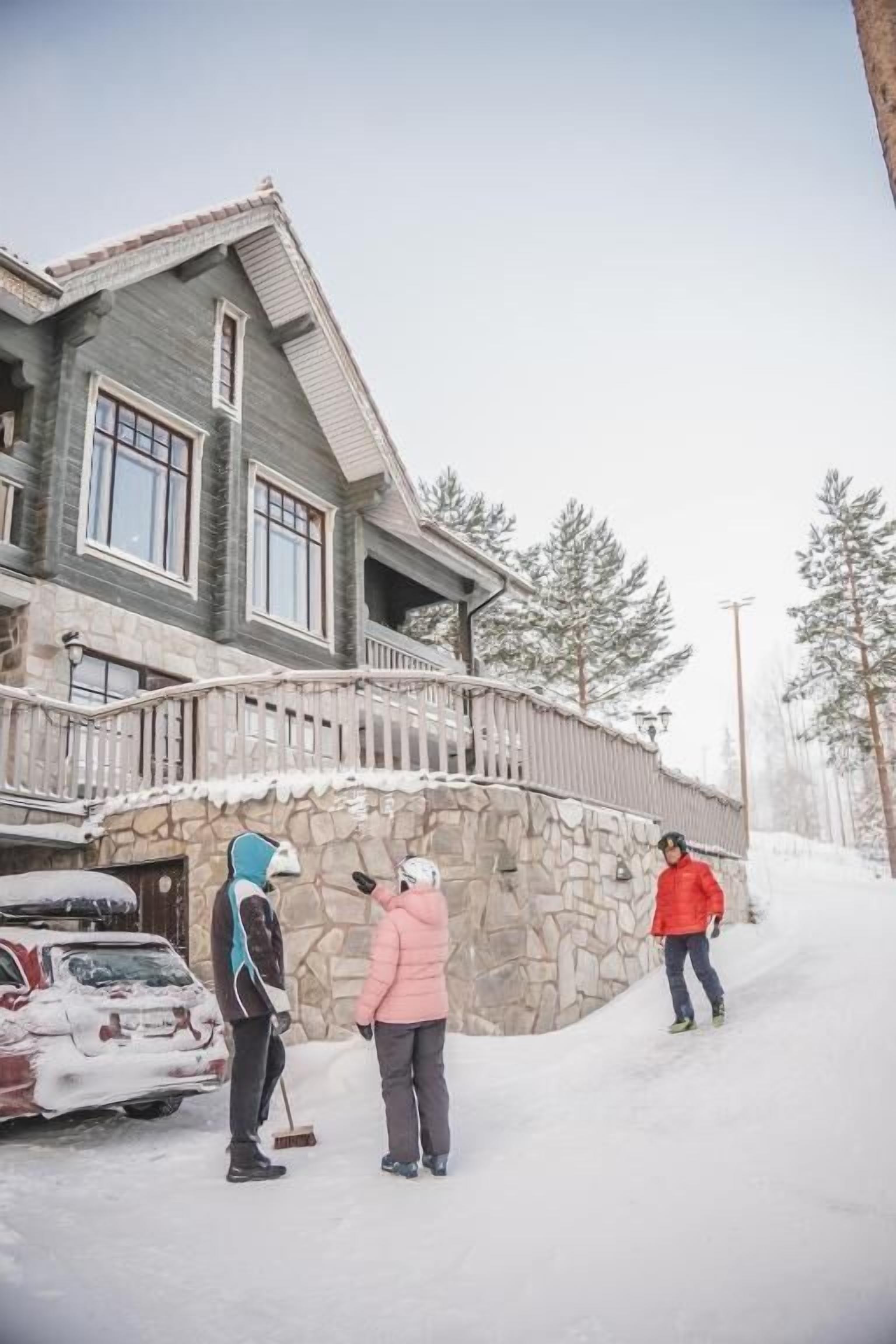 Un edificio de dos pisos con fachada de piedra, un balcón y un camino de entrada cubierto de nieve.