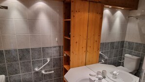 Kylpyhuone, jossa on wc, pesuallas, peili ja puinen hyllykkö.