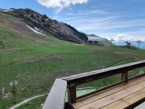 A wooden deck with a view of a mountainous landscape, a ski lift, and a building with a red roof. - Renovated studio, pets welcome - 4 guests, slope view (Plagne Aime 2000)