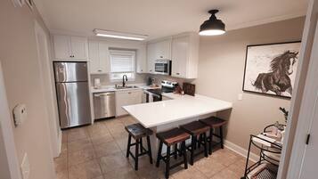 A modern kitchen with a central island, stainless steel appliances, and a dining area with stools.