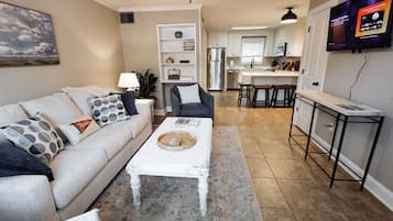 Un salon avec un canapé, une table basse et un téléviseur fixé au mur.
