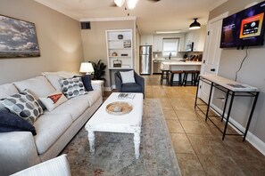 A living room with a sofa, coffee table, and a TV mounted on the wall.