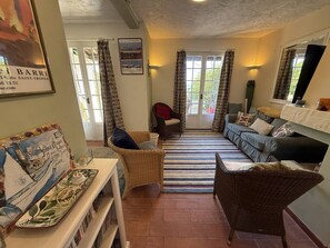 A cozy living room with wicker furniture, a striped rug, and a large window with curtains. - Mas with sea view - 3 guests (La Croix-Valmer)