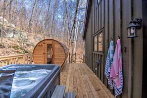 Eine Holzterrasse führt zu einer Hütte mit Whirlpool und Handtüchern, die an der Wand hängen.