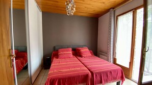 Un dormitorio con cama, espejo, puerta y ventana.