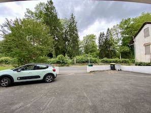 Ein Parkplatz mit einem Auto, Bäumen und einem Gebäude.