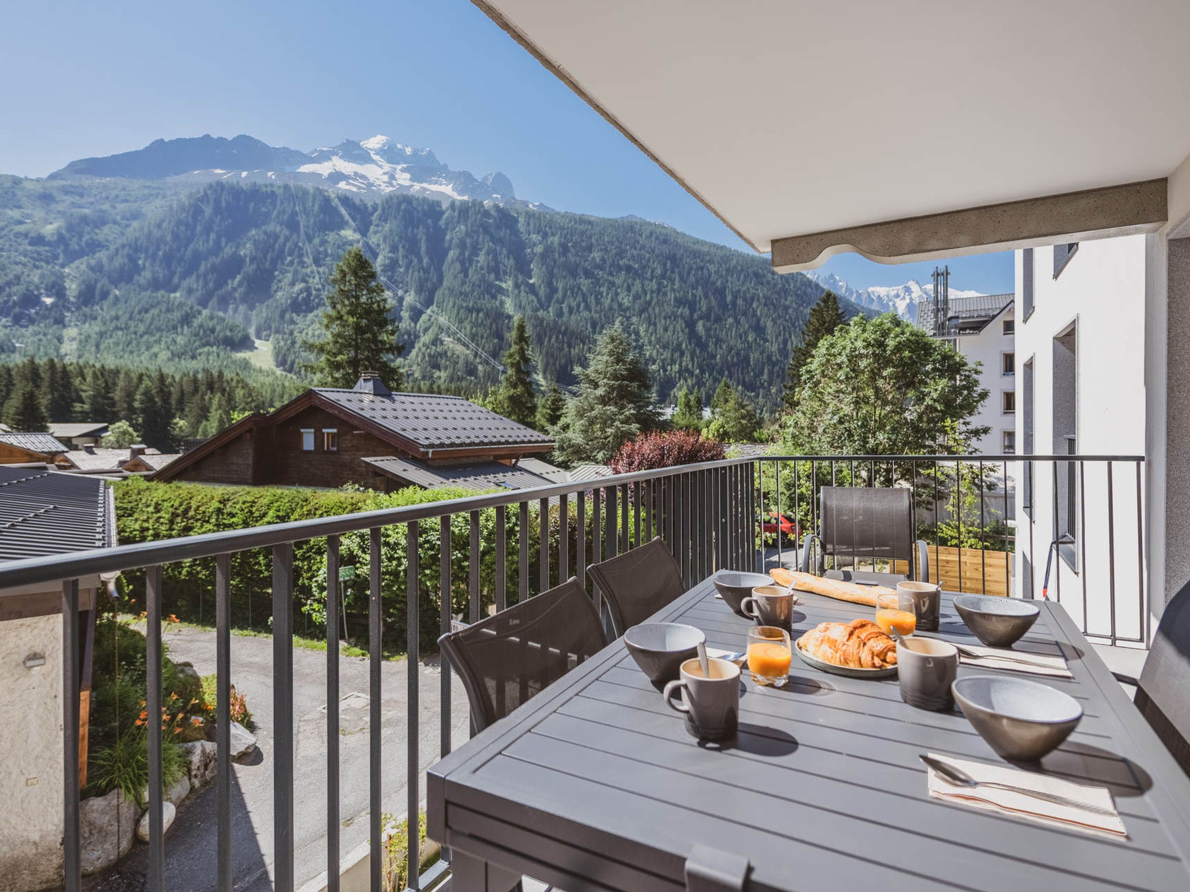 A balcony with a table set for breakfast, overlooking a mountainous landscape.