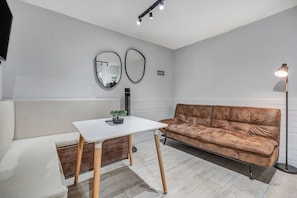 Una sala de estar moderna con una mesa blanca, un sofá de cuero marrón y una lámpara de pie.