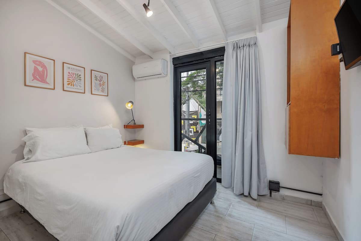 Quarto com cama, televisão na parede e quadros.
