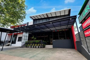 Un edificio moderno con entrada cubierta, un letrero de una cafetería y un cartel con el número de ubicación.
