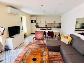 Una sala de estar con sofá, mesa de centro, televisor y comedor con sillas y mesa.