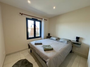 A bedroom with a bed, bedside tables, a window, and a view of the outside. - Bright apartment with AC - 4 guests (Argelès-sur-Mer)