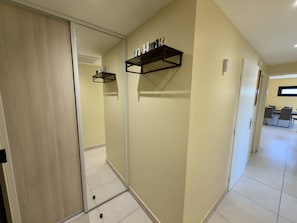 A hallway with a sliding door, a mirrored wall, and a shelf with items. - Bright apartment with AC - 4 guests (Argelès-sur-Mer)