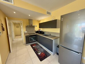 A compact kitchen with a refrigerator, oven, sink, and modern cabinetry. - Bright apartment with AC - 4 guests (Argelès-sur-Mer)