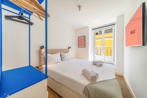 A hotel room with a bed, a blue wardrobe, a window with a view, and a 'GUEST READY' sign. - GuestReady - Carolina Building: Ground Floor Right (Lisbon)