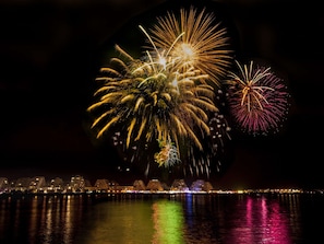 Ein nächtliches Stadtbild mit Uferpromenade und Feuerwerk.