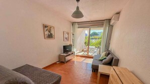 Une pièce comprenant un canapé, un téléviseur, une table en bois et un balcon avec vue.