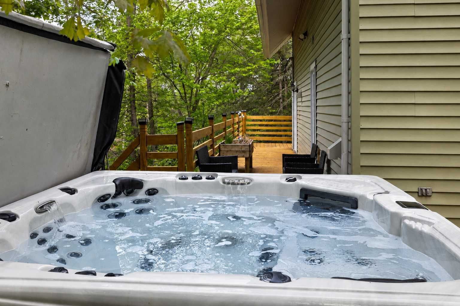 Ein Whirlpool mit einer Holzterrasse und einem Holzzaun im Hintergrund.