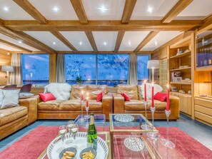 A cozy living room with leather sofas, a glass coffee table, and a view of a snowy landscape through large windows. - Spacious apartment, panoramic view - 14 guests (Tignes)