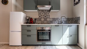 A compact kitchen with a built-in oven, a coffee maker, and a kettle on the countertop.
