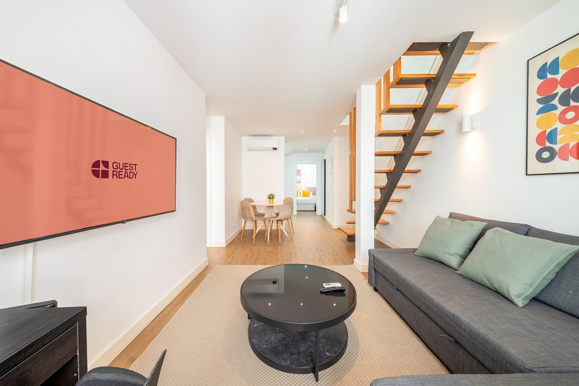 A modern living room with a sofa, a coffee table, and a TV mounted on the wall.