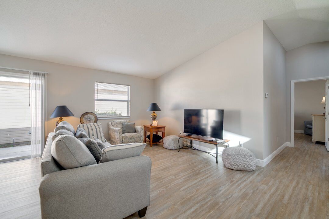 A spacious living room with a large flat-screen TV, a sofa, a coffee table, and a TV stand.