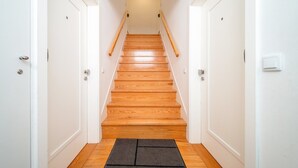 A staircase with wooden steps and a black mat at the bottom. - GuestReady - Carolina Building: Ground Floor Left (Lisbon)