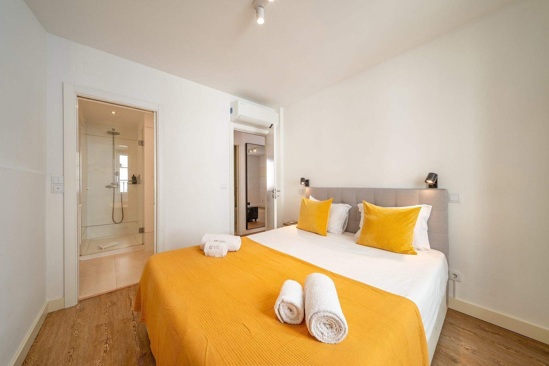 A hotel room with a bed, a shower, and a door leading to another room.