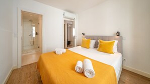 A hotel room with a bed, a shower, and a door leading to another room. - GuestReady - Carolina Building: Ground Floor Left (Lisbon)