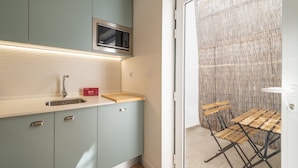 A compact kitchen with a microwave, a sink, and a wooden cutting board. - GuestReady - Carolina Building: Ground Floor Left (Lisbon)