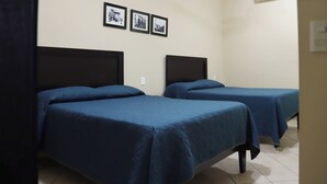 A room with two beds, a ceiling fan, and three framed pictures on the wall.