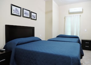 Un dormitorio con dos camas, un cabecero negro y tres cuadros en la pared.