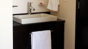 A bathroom with a white sink, a mirror, a towel rack, and a light fixture.