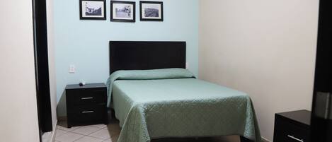 A bedroom with a bed, a nightstand, a dresser, and three framed pictures on the wall.