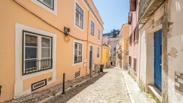 Una stretta strada acciottolata fiancheggiata da edifici con balconi e finestre.