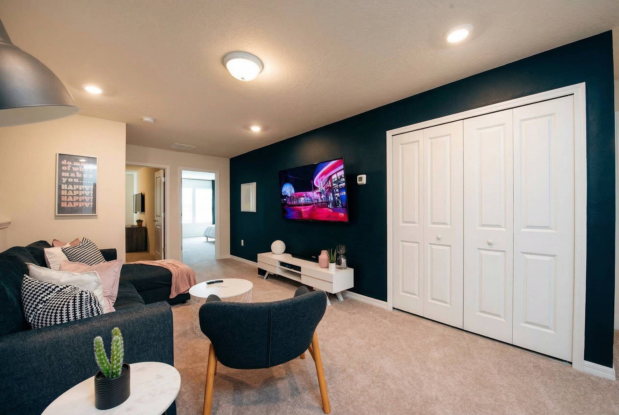 A modern living room with a flat-screen TV, a sofa, a coffee table, and a white cabinet.
