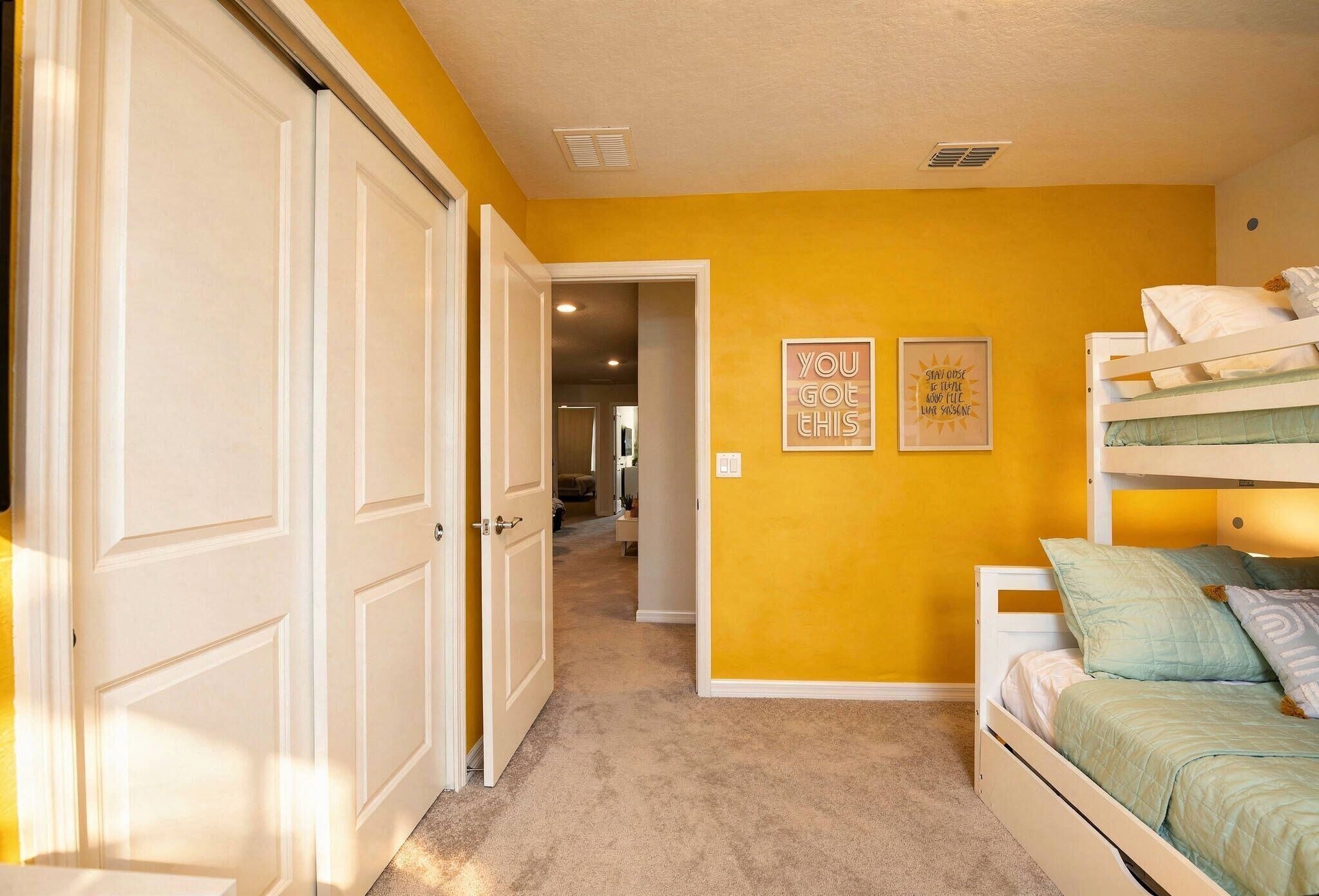 A bedroom with a bunk bed, a hallway, and a door leading to another room.
