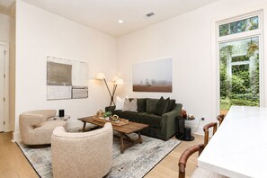 Ein Wohnzimmer mit Sofa, Sesseln, Couchtisch und einem Bild an der Wand.