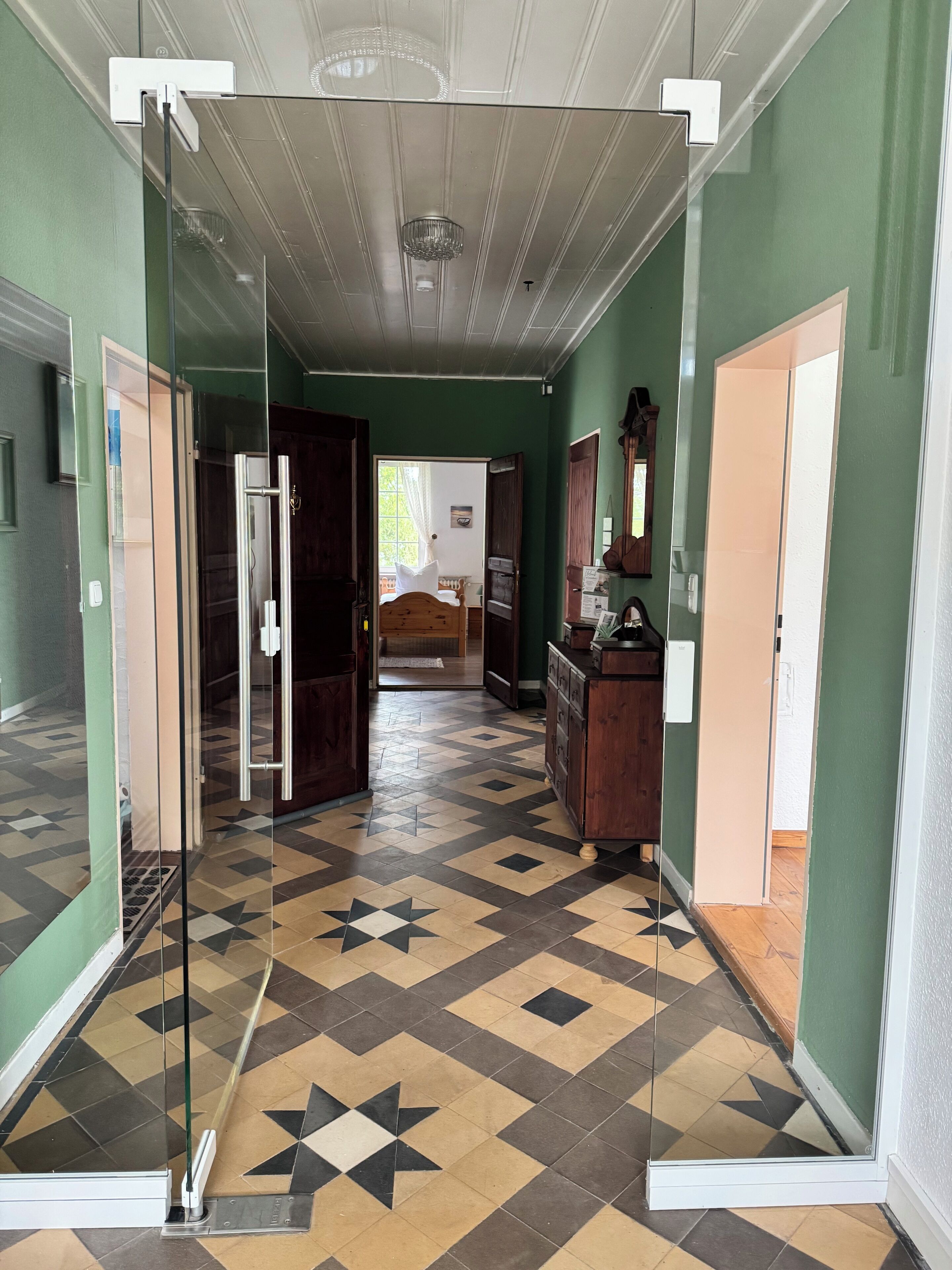 A hallway with a patterned floor, a refrigerator, and a wooden cabinet.