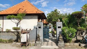 A bungalow with a tiled roof, a gate, and a statue. - Belvilla near Sampalan Beach formerly Ar (Penida Island)