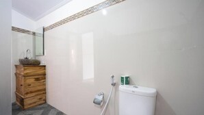 A bathroom with a toilet, a wooden cabinet, a mirror, and a patterned tile border. - Belvilla near Sampalan Beach formerly Ar (Penida Island)