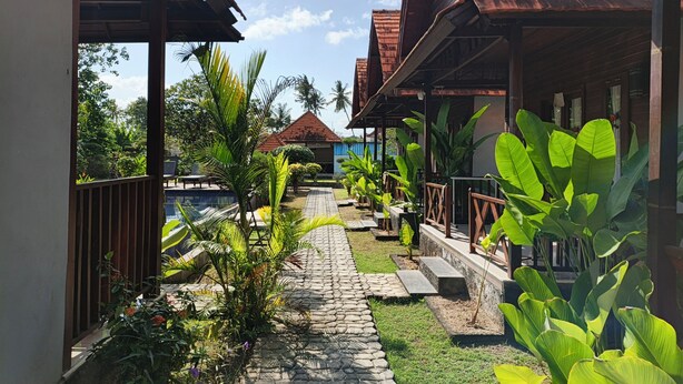 A pathway leading to a building with a red roof, surrounded by lush greenery and a clear sky. - Belvilla near Sampalan Beach formerly Ar (Penida Island)