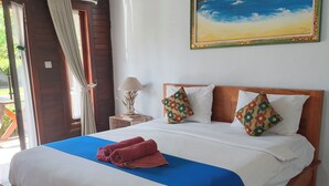 A wooden bed with white and blue bedding, a painting of a coastal scene, and a lamp on a bedside table. - Belvilla near Sampalan Beach formerly Ar (Penida Island)