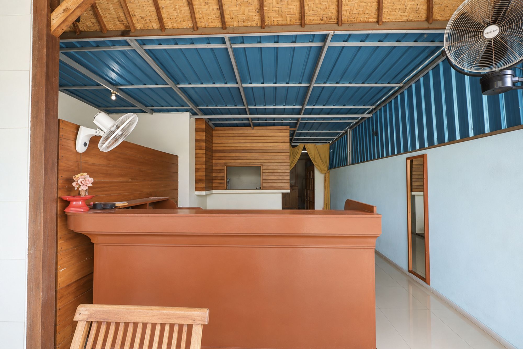 Un área de recepción con mostrador de madera, techo azul y un ventilador.