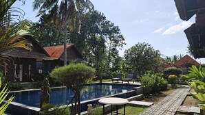 A pool area with a stone pathway, lounge chairs, and tropical vegetation. - Belvilla near Sampalan Beach formerly Ar (Penida Island)