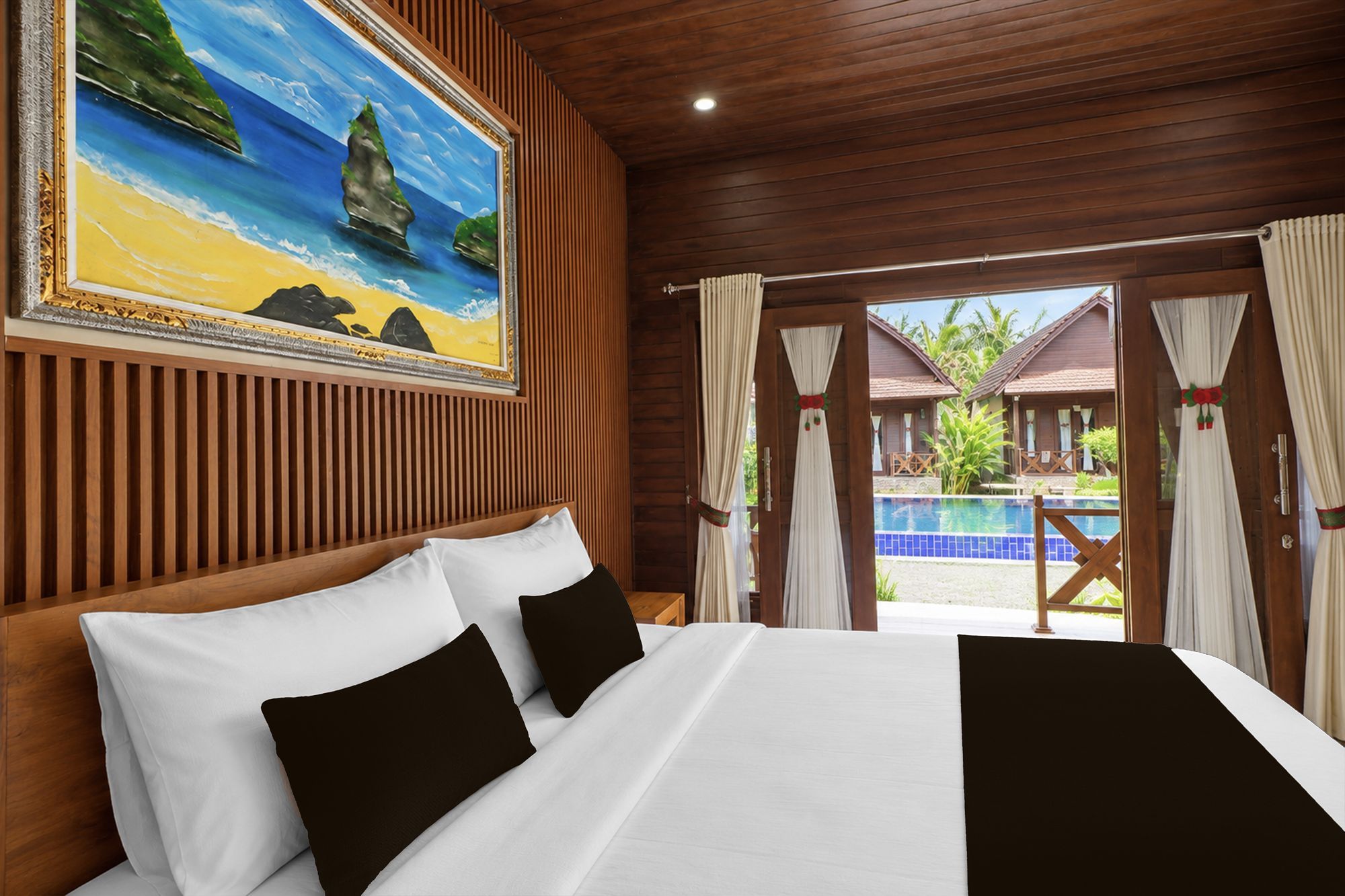 Habitación de hotel con cama, un cuadro de una playa y vistas a una piscina y villas.