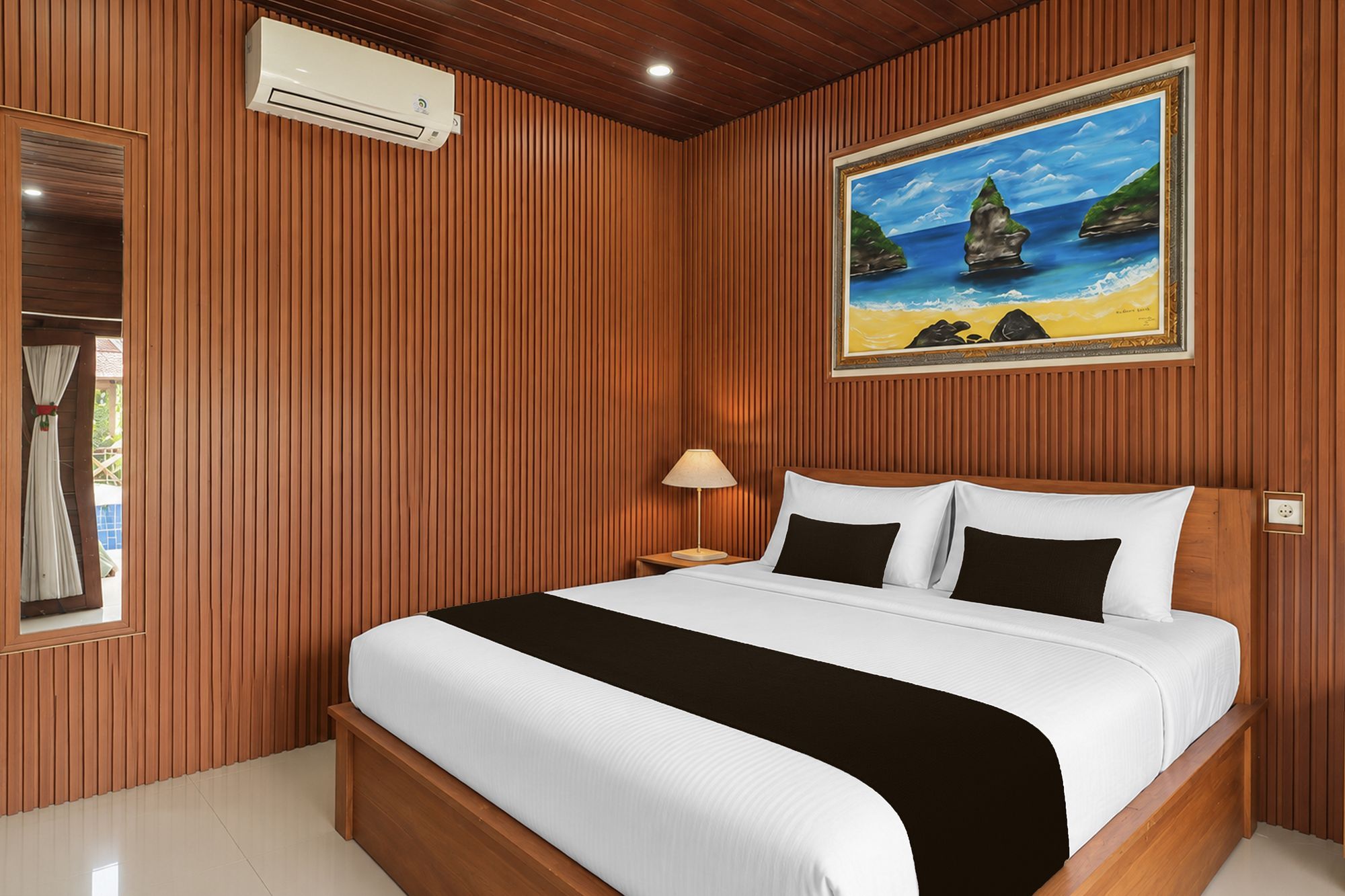 A hotel room with a bed, a painting of a beach scene, and a window with curtains.