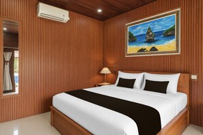 Habitación de hotel con cama, un cuadro de una escena de playa y una ventana con cortinas.