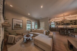 Ein geräumiges Wohnzimmer mit einer großen Eckcouch, einem Couchtisch und einem Essbereich mit einem Holztisch und Stühlen.