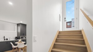 Una cocina moderna con armarios oscuros, encimera blanca y una zona de comedor con una pequeña mesa y sillas.
